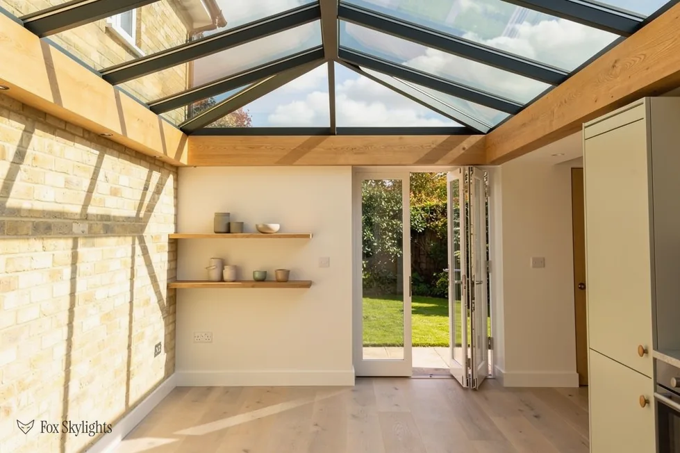 Roof lantern filling an extension with light, oak beam and doors open to the garden