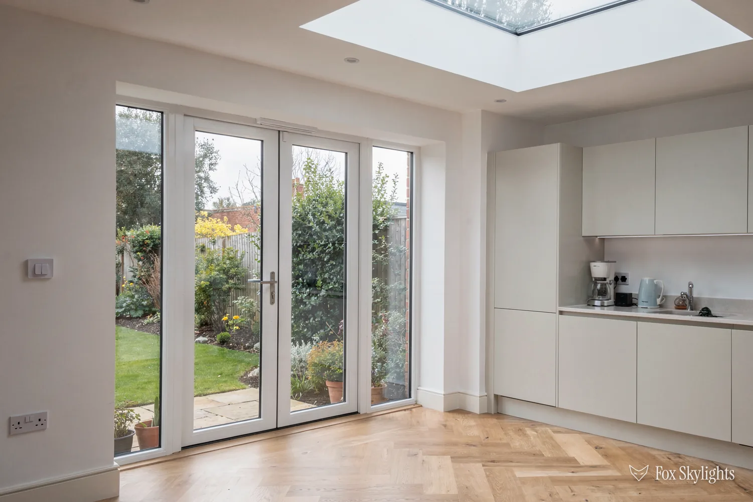 Flat rooflight above a white kitchen extension with French doors to the lawn