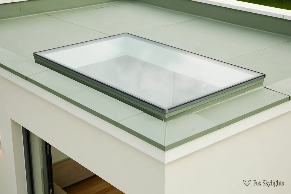 Frameless glass rooflight unit sitting on a white rendered upstand