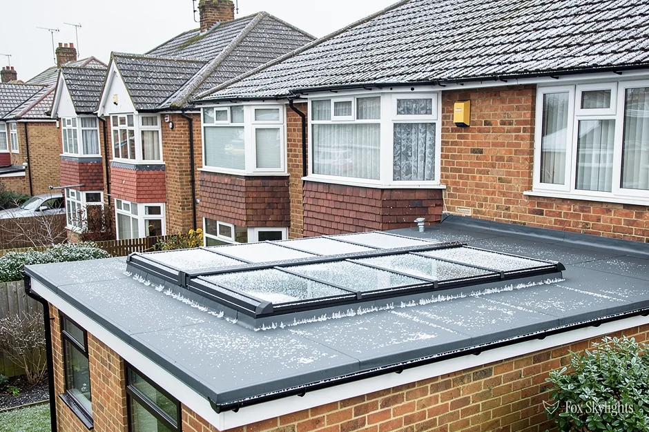 Long multi pane flat rooflight on a brick extension behind semi detached houses