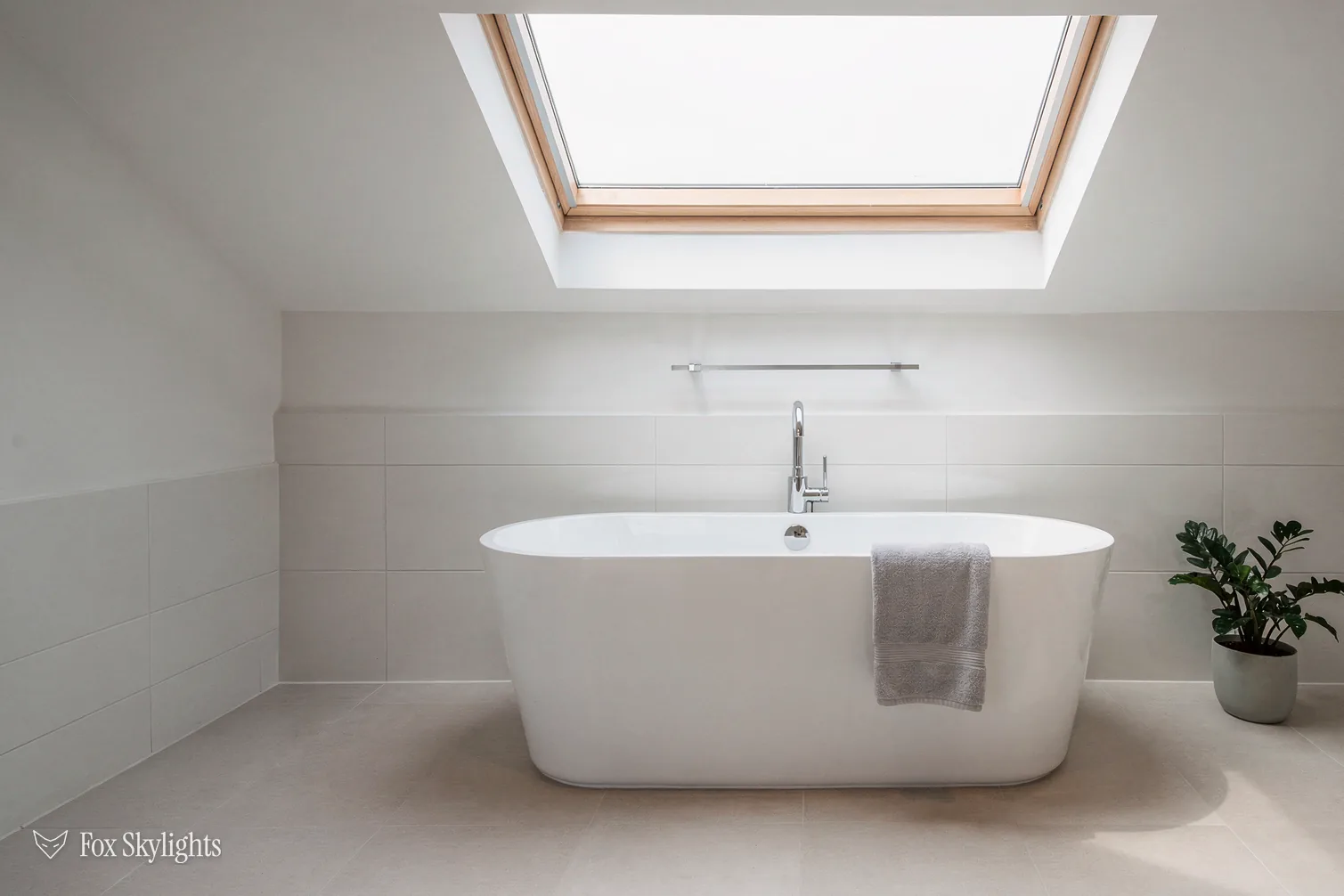Roof window above a freestanding bath in a white loft bathroom