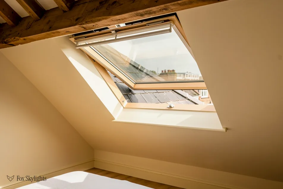 Pine roof window tilted open in a loft with exposed timber beams