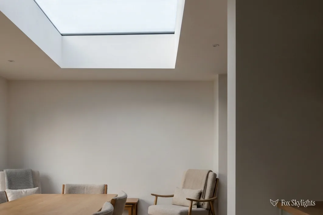 Flat rooflight above a quiet sitting area with plain white walls