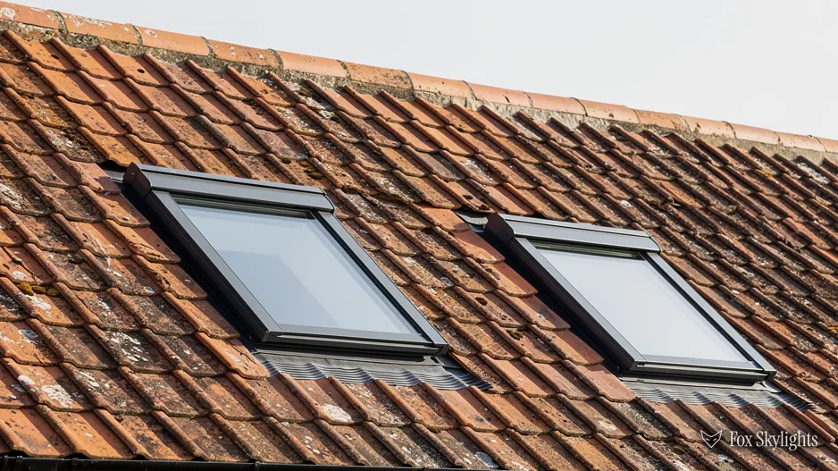 Close view of two low profile rooflights lying flush in clay roof tiles