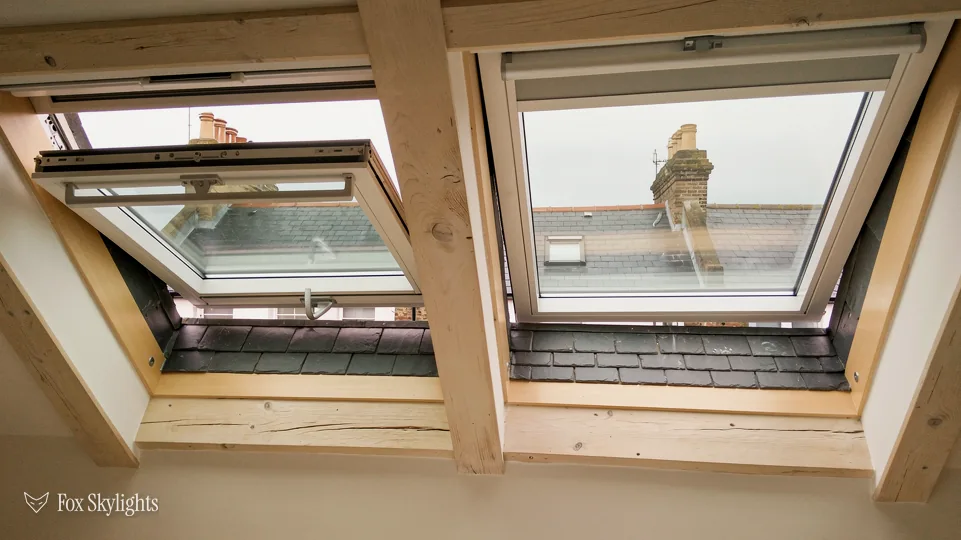 Pair of pine roof windows between loft rafters, one tilted open