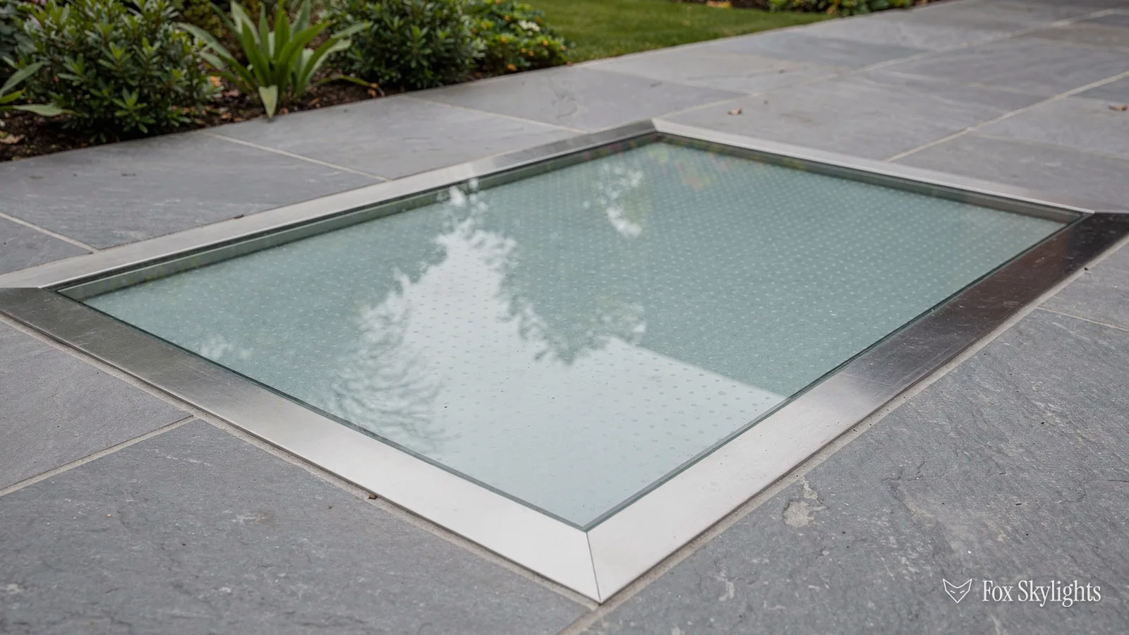Walk on glass rooflight with steel trim set into slate paving