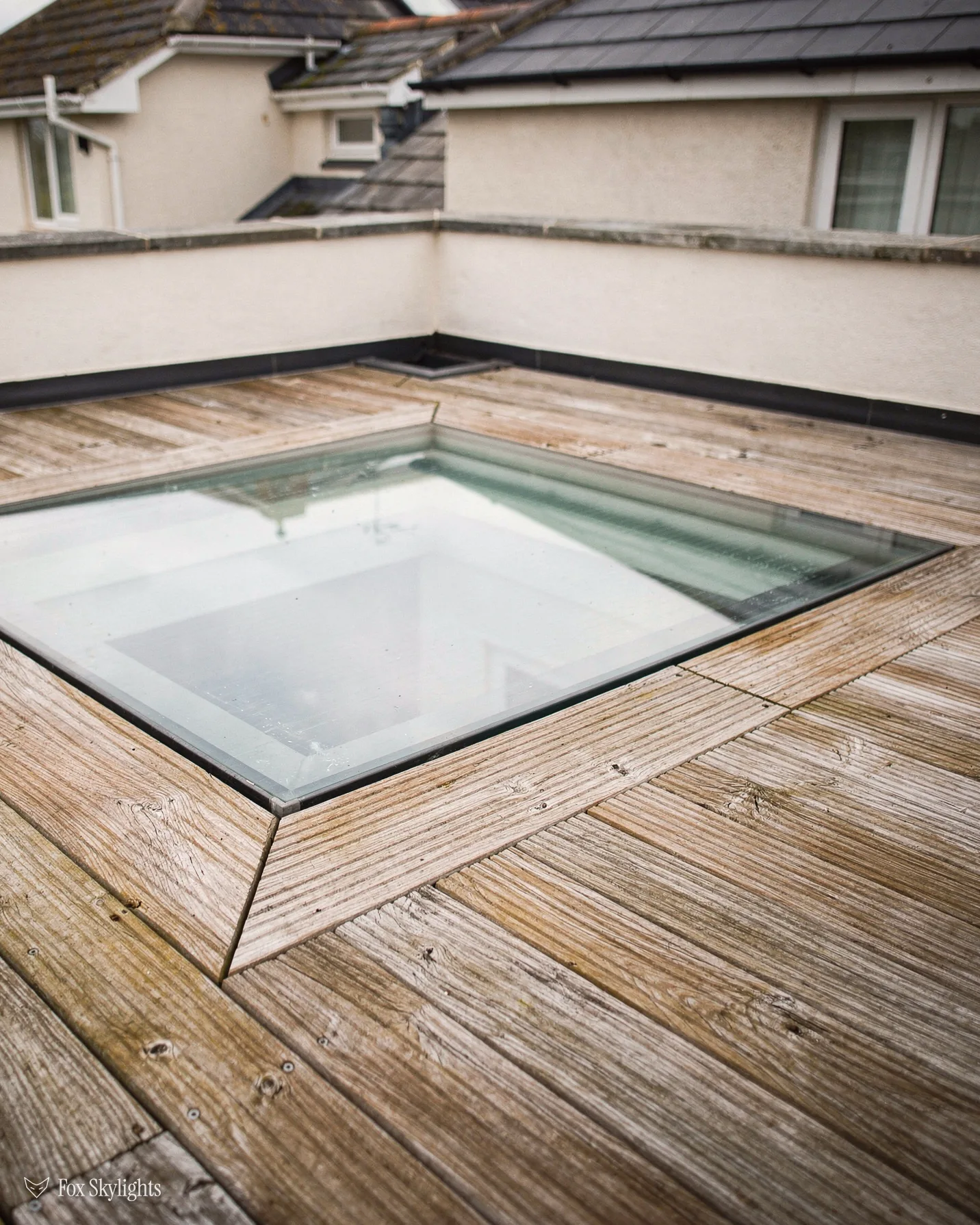 Walk on glass rooflight set in timber decking on a rendered roof terrace