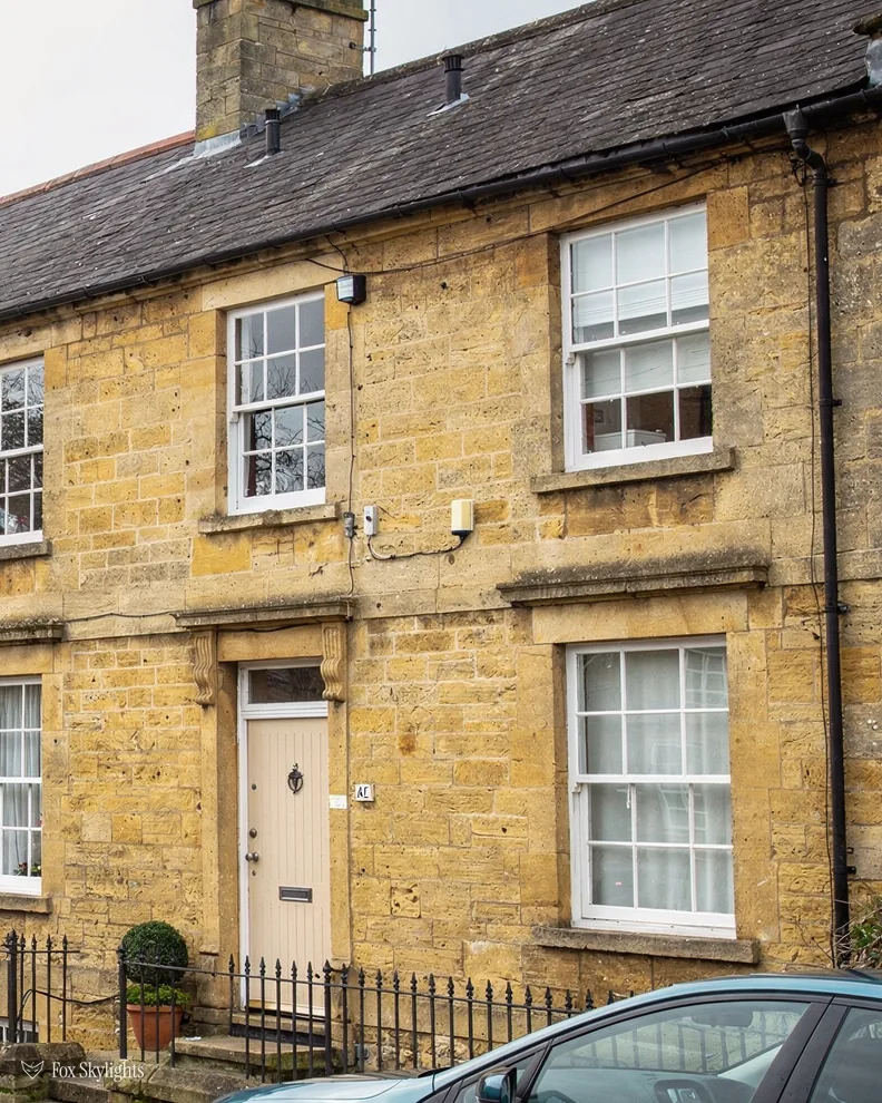 Honey stone house with sash windows and a slate roof