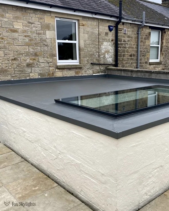 Flat rooflight on a white rendered extension below a stone house with sash windows