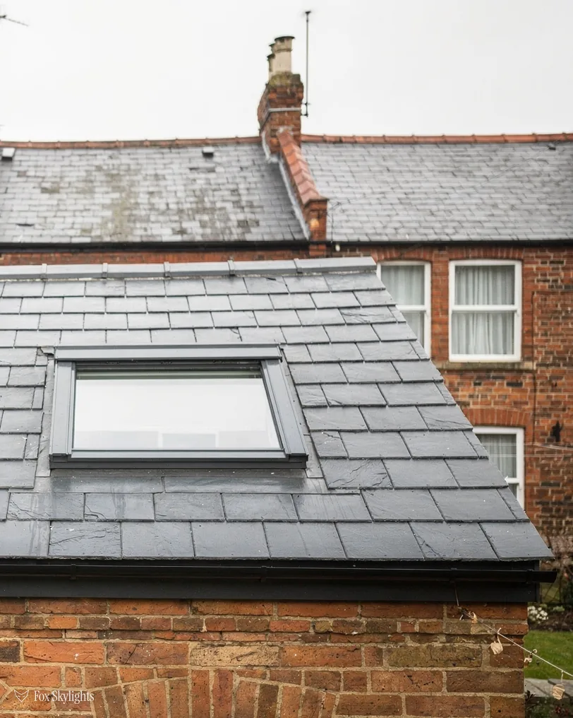 Roof window in the grey slate roof of a red brick rear extension