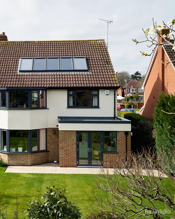 Rendered detached house with roof windows in its tile roof and rear extension