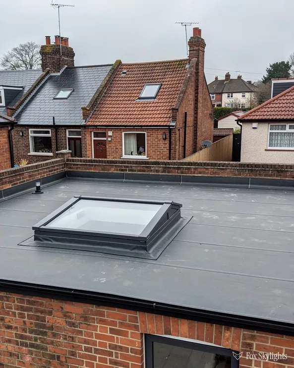 Flat rooflight on the membrane roof of a brick extension behind terraced houses