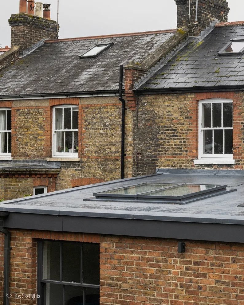 Flat rooflight on a red brick extension behind yellow brick terraced houses