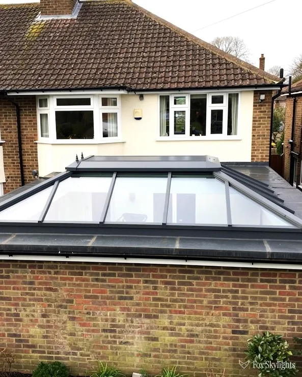 Roof lantern on a flat roof extension behind a brick garden wall, tiled house roof above