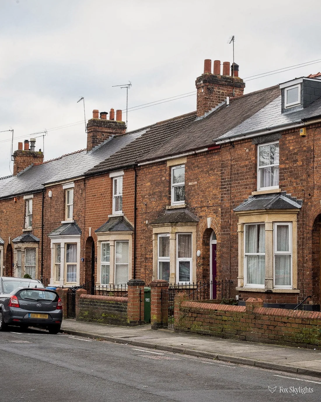 Victorian terrace of red brick houses with tall chimneys and slate roofs on a street