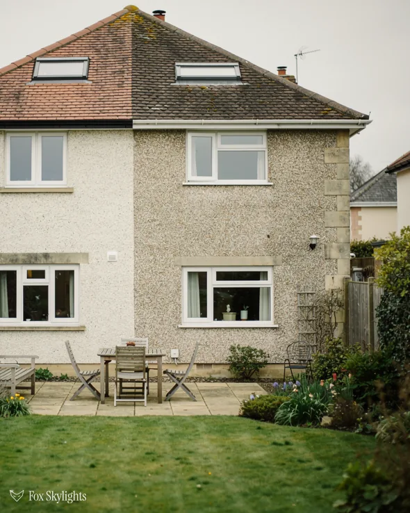 Pale stone semi with two roof windows in its tile roof above a patio garden