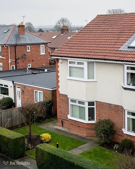 Rendered semi with brick lower walls and tidy back gardens beside tiled roofs