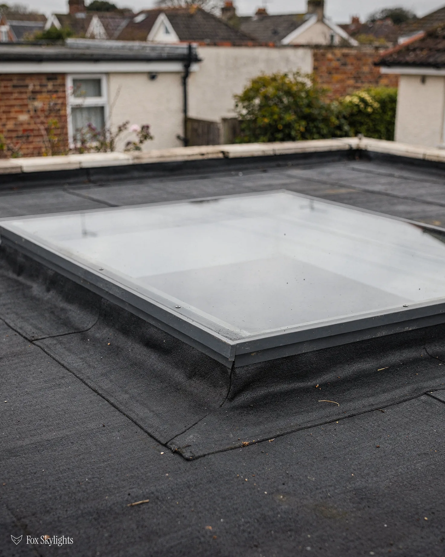 Flat rooflight on a black membrane roof among suburban houses